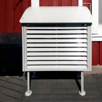 Ilmalämpöpumppu asennettuna maatelineellä ja varustettu metallisella suojakotelolla.